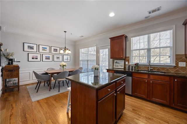 kitchen with a kitchen island, a sink, visible vents, dishwasher, and decorative light fixtures