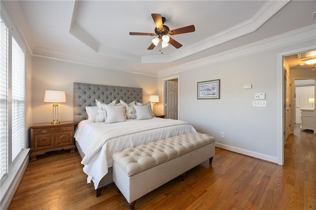 bedroom featuring wood finished floors, baseboards, a tray ceiling, attic access, and crown molding