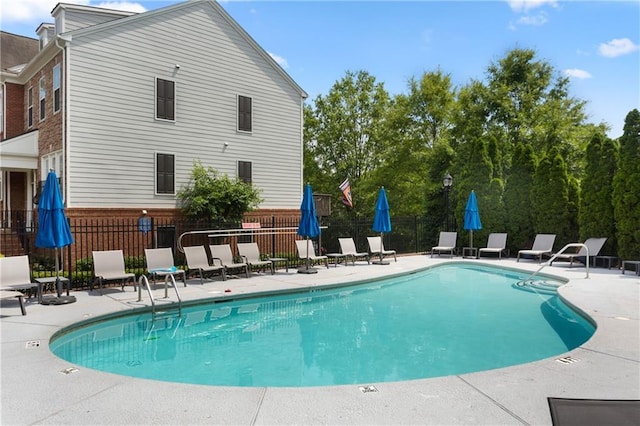 community pool with a patio area and fence