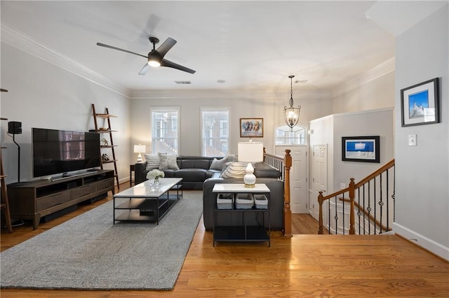 living room featuring light wood-style floors, baseboards, visible vents, and crown molding