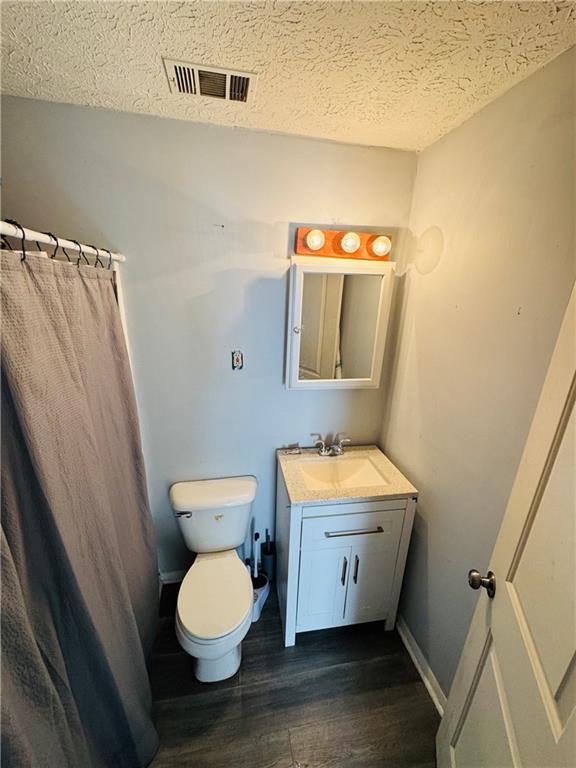 bathroom with vanity, hardwood / wood-style flooring, a textured ceiling, and toilet