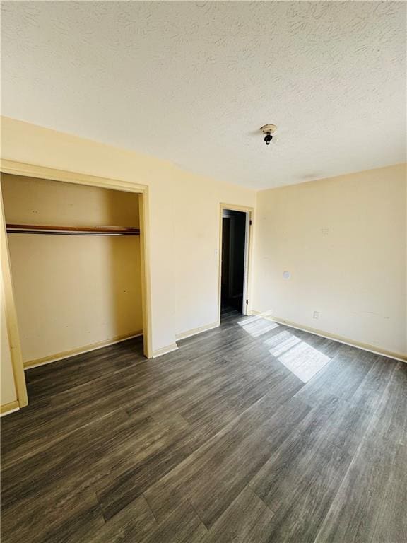 unfurnished bedroom featuring a textured ceiling, a closet, and dark hardwood / wood-style flooring