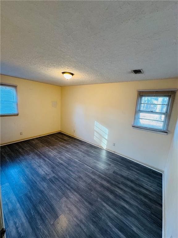 empty room featuring dark wood-type flooring and a textured ceiling