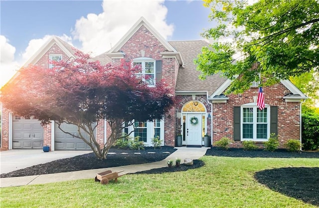 traditional-style home featuring a front yard, concrete driveway, brick siding, a shingled roof, and a garage