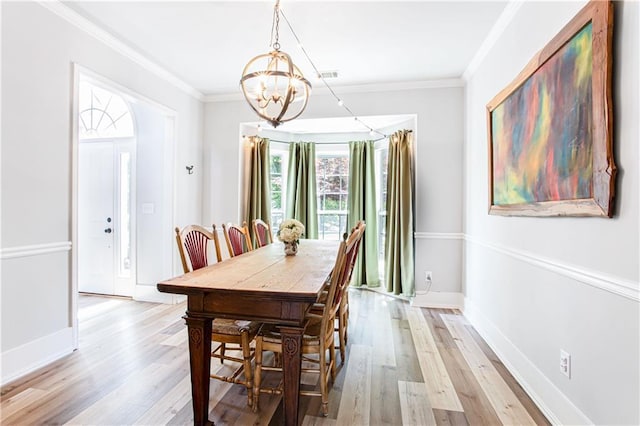 dining space featuring a chandelier, light wood-style floors, crown molding, and baseboards