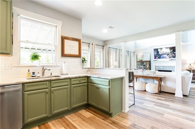 kitchen featuring green cabinetry, stainless steel dishwasher, a sink, a peninsula, and recessed lighting