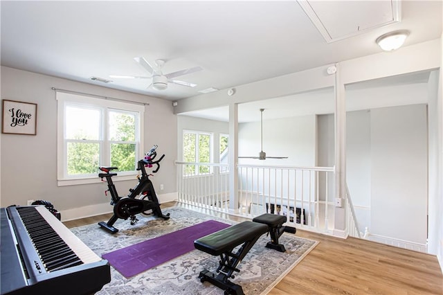 exercise area with a ceiling fan, wood finished floors, attic access, and baseboards