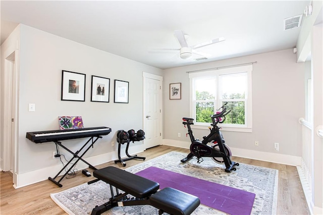 workout room featuring a ceiling fan, light wood-style flooring, and baseboards
