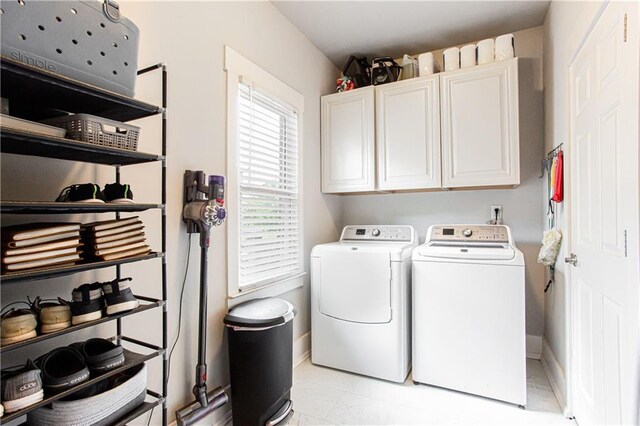 clothes washing area with cabinet space, washer and clothes dryer, light marble finish floors, and baseboards