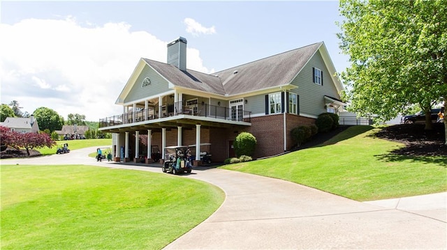 back of property with brick siding, a yard, a chimney, and a balcony
