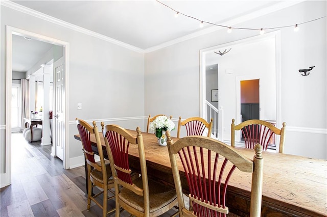 dining room with wood finished floors, ornamental molding, and baseboards