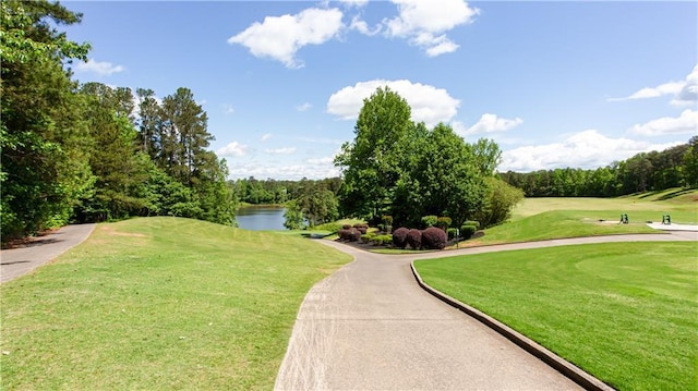 view of community featuring golf course view, a water view, and a lawn