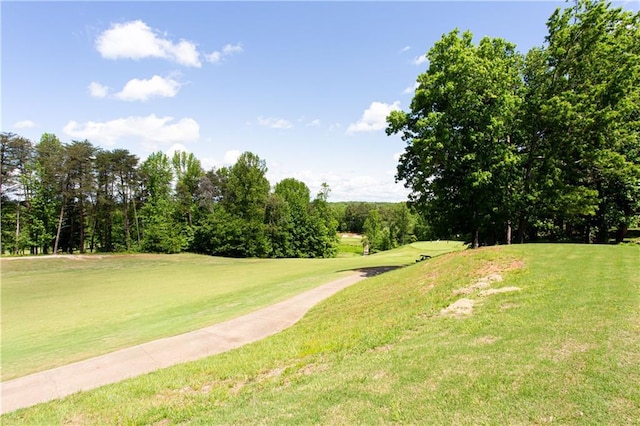 view of home's community with golf course view, a lawn, and view of scattered trees