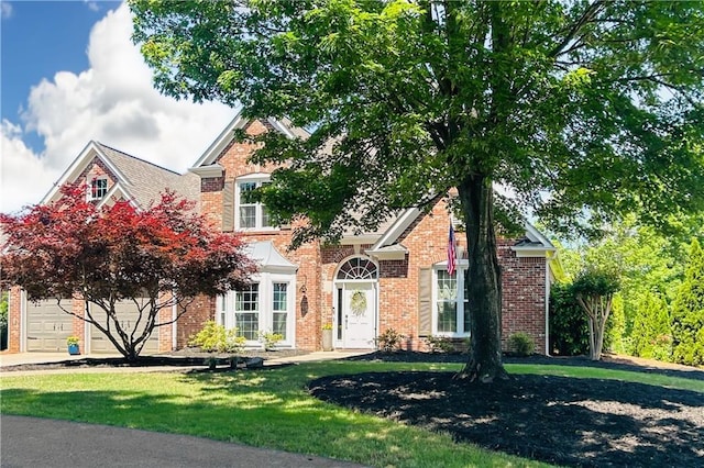 view of front of home with brick siding, a front lawn, and an attached garage