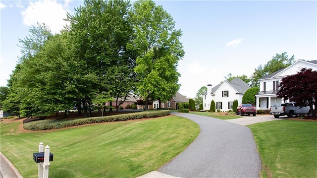 view of home's community featuring curved driveway, a residential view, and a yard