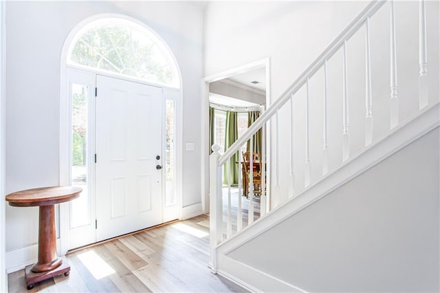 entryway featuring stairs, wood finished floors, and a towering ceiling
