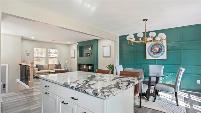 kitchen featuring a kitchen island, pendant lighting, white cabinetry, a notable chandelier, and dark wood-type flooring