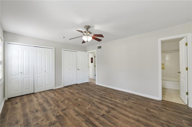 2825 NE Expy NE Unit F003, Atlanta, GA 30345 - unfurnished bedroom featuring dark wood-style floors, multiple closets, ensuite bathroom, and a ceiling fan