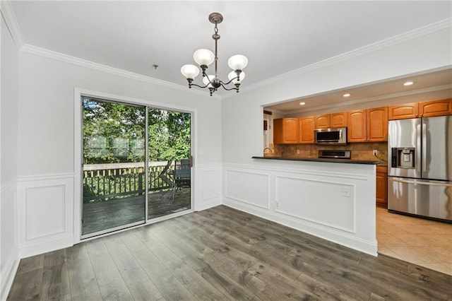 2825 NE Expy NE Unit F003, Atlanta, GA 30345 - kitchen with stainless steel appliances, a chandelier, crown molding, dark countertops, and wood finished floors