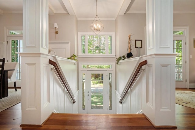 entrance foyer featuring a decorative wall, wood finished floors, stairway, a chandelier, and crown molding