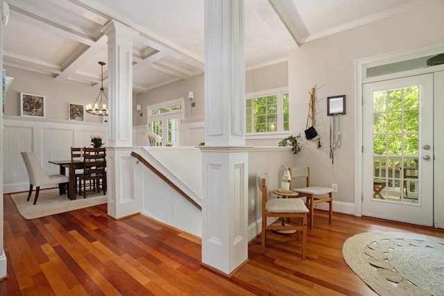 stairs with decorative columns, a decorative wall, beamed ceiling, wood finished floors, and a chandelier