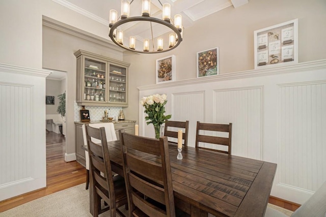 dining area with a chandelier, light wood-style flooring, crown molding, beam ceiling, and coffered ceiling