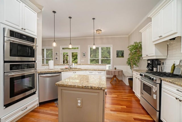 kitchen featuring stainless steel appliances, a sink, a peninsula, decorative backsplash, and a center island