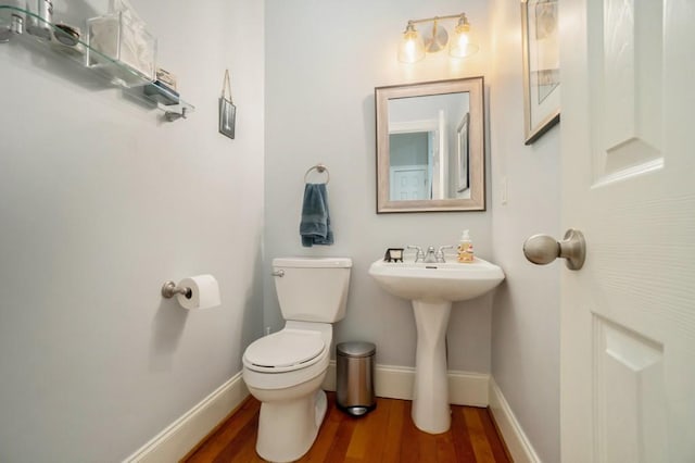 bathroom with wood finished floors, toilet, baseboards, and a sink