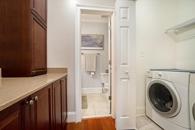 clothes washing area with baseboards and light wood-type flooring