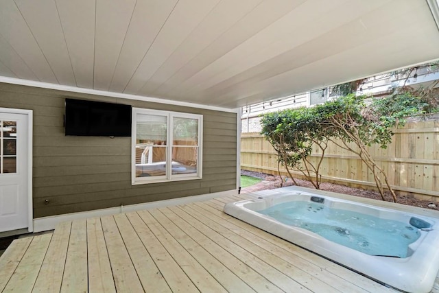wooden deck with an indoor hot tub and fence
