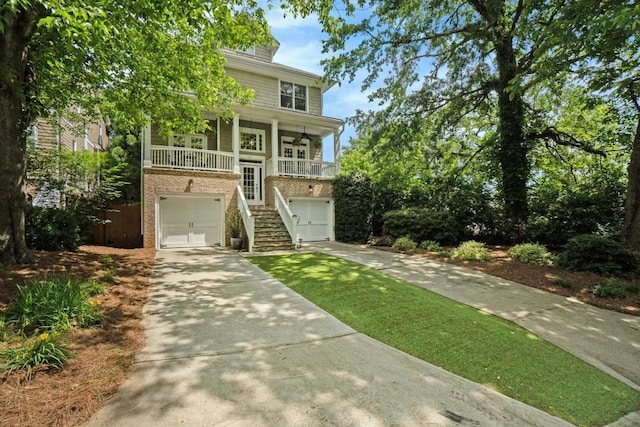 view of front of property with stairway, concrete driveway, brick siding, a porch, and an attached garage
