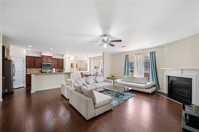 living area featuring ceiling fan, dark wood-type flooring, a glass covered fireplace, and recessed lighting