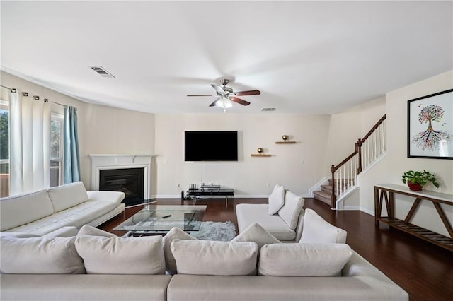 living room with wood finished floors, ceiling fan, stairs, a glass covered fireplace, and baseboards