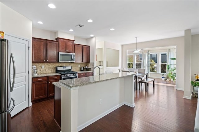 kitchen with appliances with stainless steel finishes, dark wood-type flooring, tasteful backsplash, light stone countertops, and recessed lighting