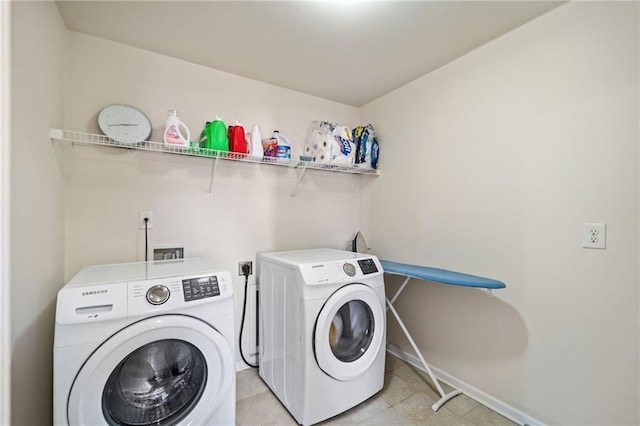 laundry room featuring washer and clothes dryer, baseboards, and light tile patterned floors