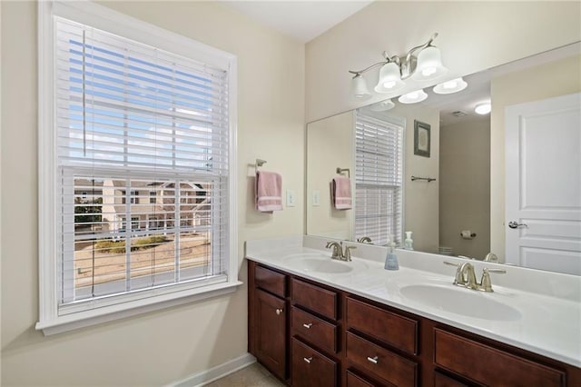 full bath with toilet, plenty of natural light, double vanity, and baseboards