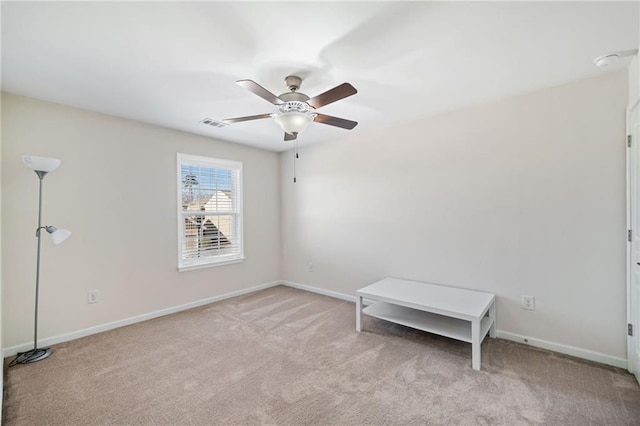 spare room featuring a ceiling fan, light colored carpet, and baseboards