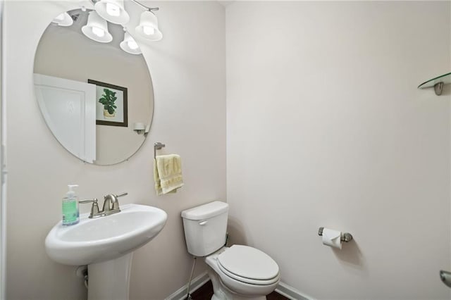 bathroom with toilet, baseboards, and a sink