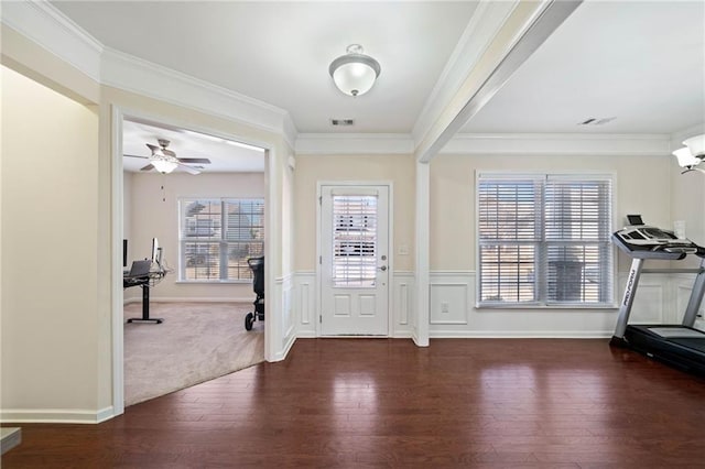 foyer with crown molding, wood finished floors, ceiling fan, and a wainscoted wall