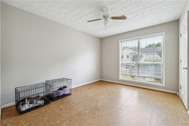 spare room featuring a textured ceiling, baseboards, and a ceiling fan