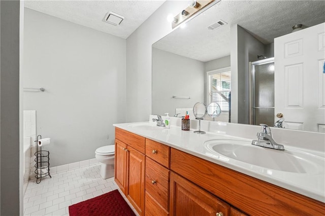 full bathroom featuring a textured ceiling, a shower with door, toilet, double vanity, and tile patterned floors