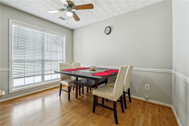 dining room featuring a textured ceiling, light wood-style flooring, ceiling fan, and baseboards