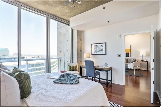 bedroom with expansive windows, baseboards, and wood finished floors