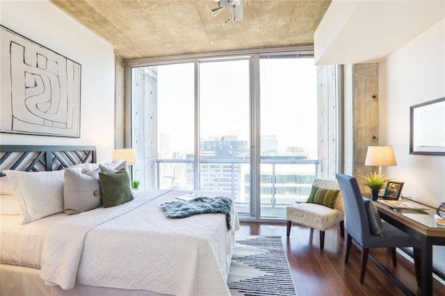 bedroom featuring floor to ceiling windows, a view of city, and wood finished floors