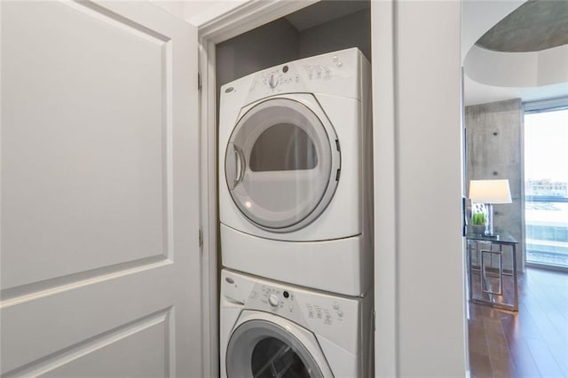 washroom featuring laundry area, wood finished floors, and stacked washing maching and dryer