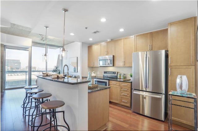 kitchen featuring stainless steel appliances, a kitchen breakfast bar, visible vents, and wood finished floors