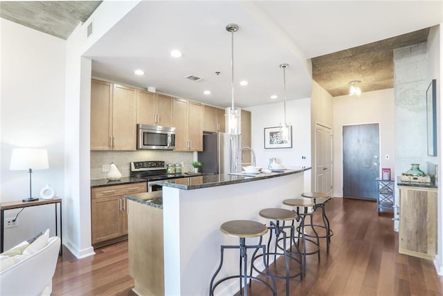 kitchen with visible vents, a breakfast bar, tasteful backsplash, stainless steel appliances, and dark wood-style flooring