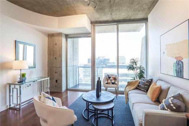 living room featuring dark wood-style flooring, a view of city, baseboards, and expansive windows