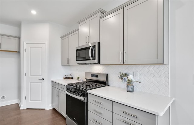 kitchen featuring decorative backsplash, appliances with stainless steel finishes, dark hardwood / wood-style flooring, and gray cabinetry