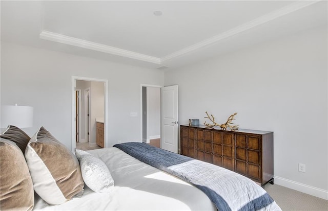 bedroom with ornamental molding, light colored carpet, a raised ceiling, and ensuite bath